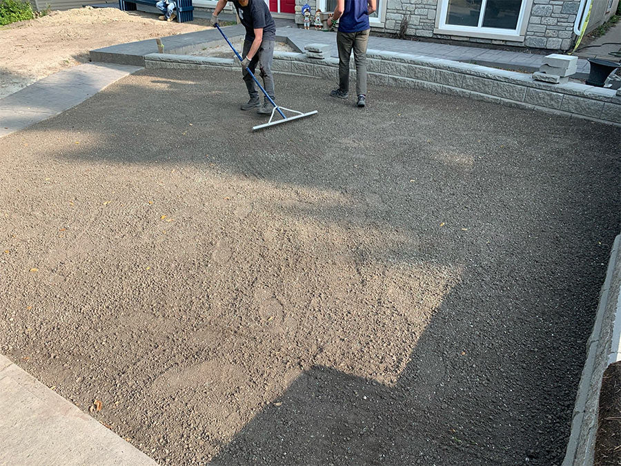 Two landscapers preparing some soil for fresh sod to be installed